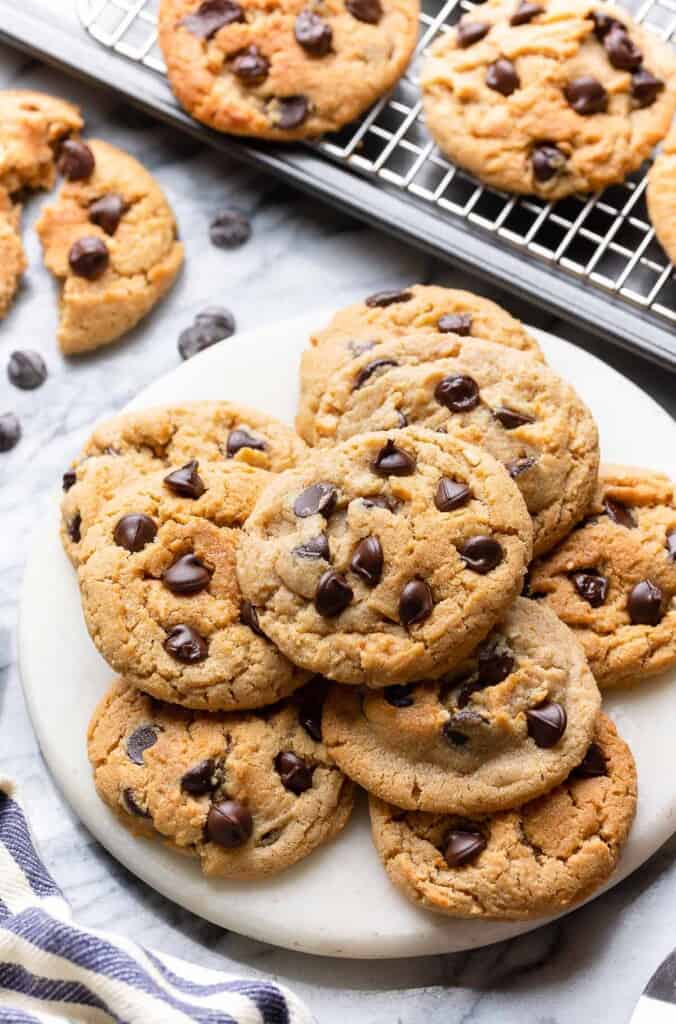 Chocolate Chip Peanut Butter Cookies made with Millet Flour on a small platter with more cooking cooling on a wire rack behind