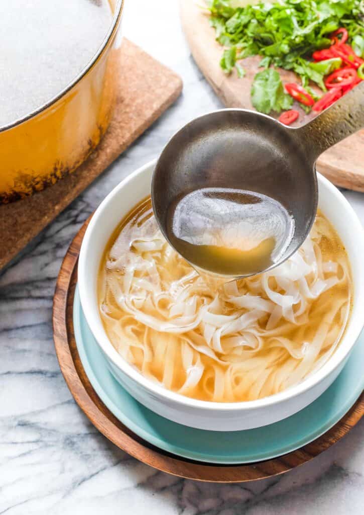broth pouring into a bowl of noodles