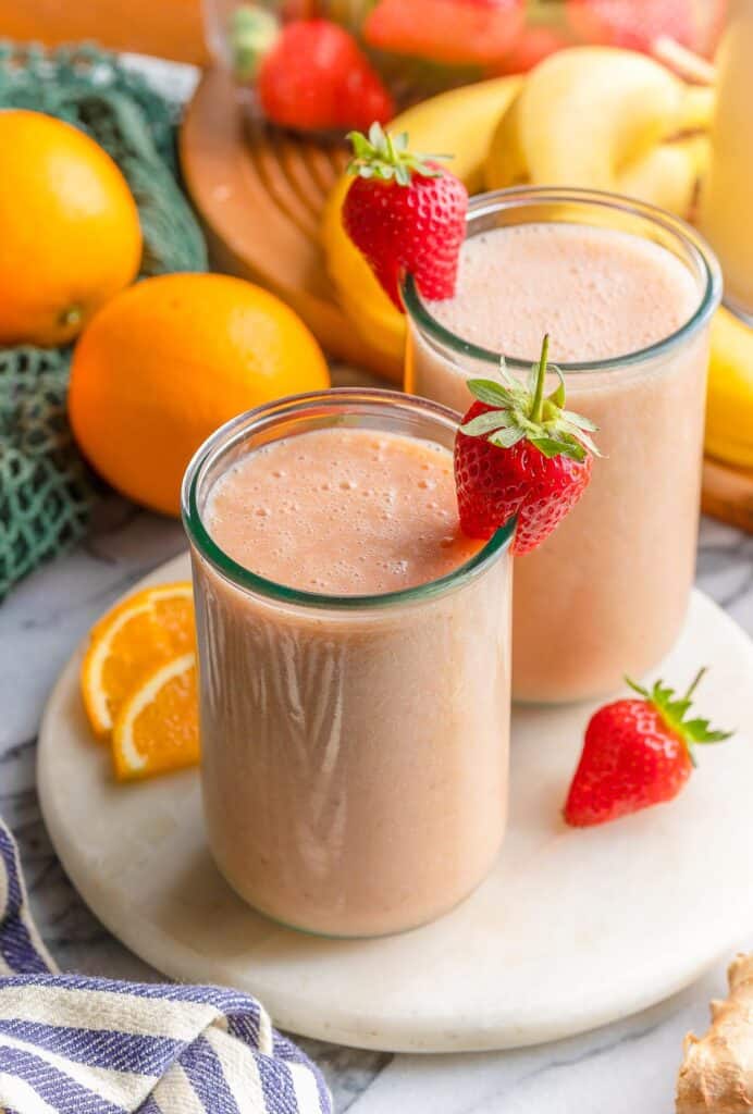 Citrusy Ginger Smoothie in a couple of glasses with fruit garnished on a serving plate