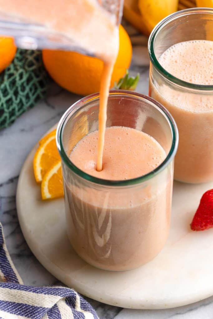 a blender full of a strawberry ginger smoothie pouring into a couple of glassed 