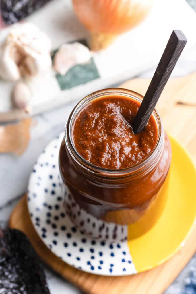 enchilada sauce in a jar with a spoon on a plate