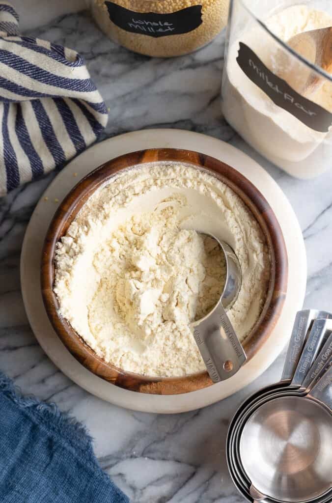 millet flour in a bowl with a measuring cup in it