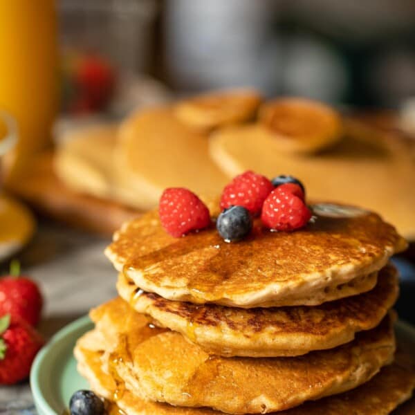 millet pancakes stacked on a plate with fresh berries