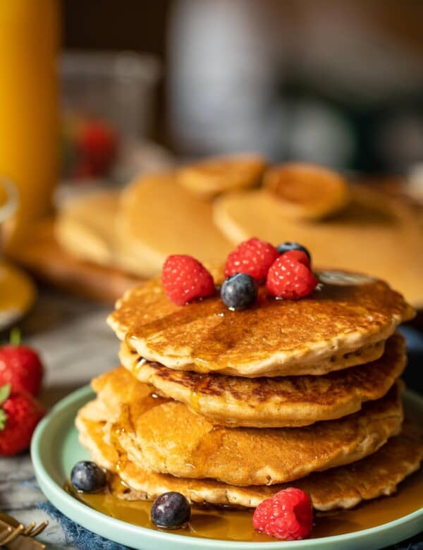 millet pancakes stacked on a plate with fresh berries