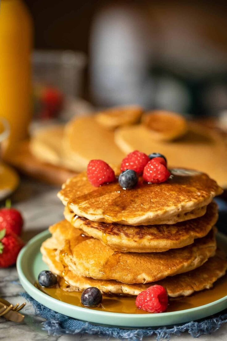 millet pancakes stacked on a plate with fresh berries