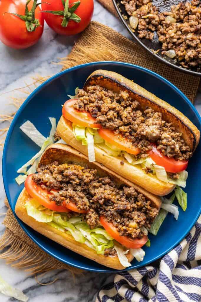 two Chopped Cheese Sandwich buns on gluten free bread filled with shredded lettuce and tomato slices