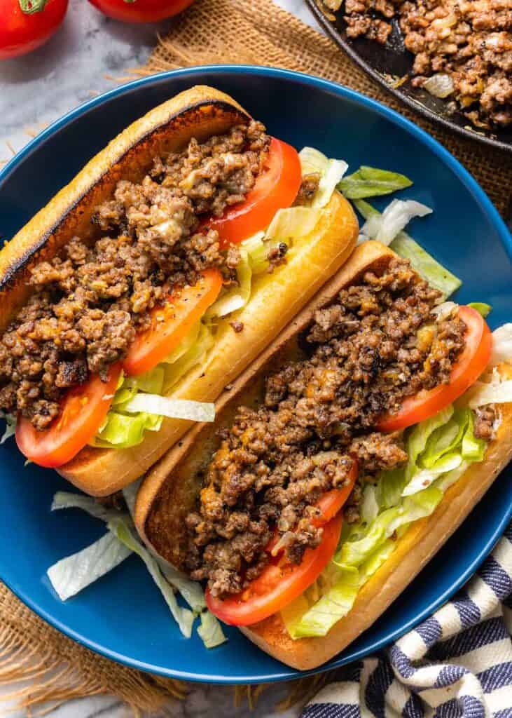 gluten free chopped cheese sandwiches: two buns filled with shredded lettuce, tomatoes and seasoned beef on a plate