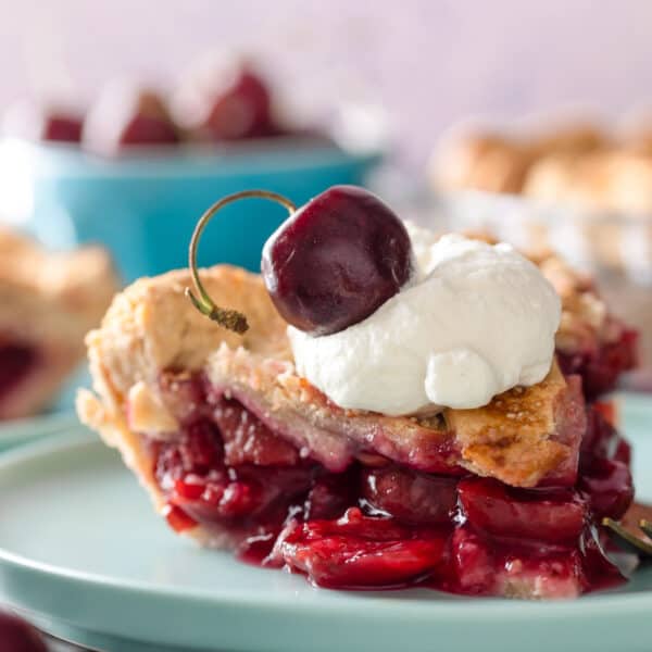 a slice of gluten free cherry pie on a plate topped with whipped cream and a fresh cherry