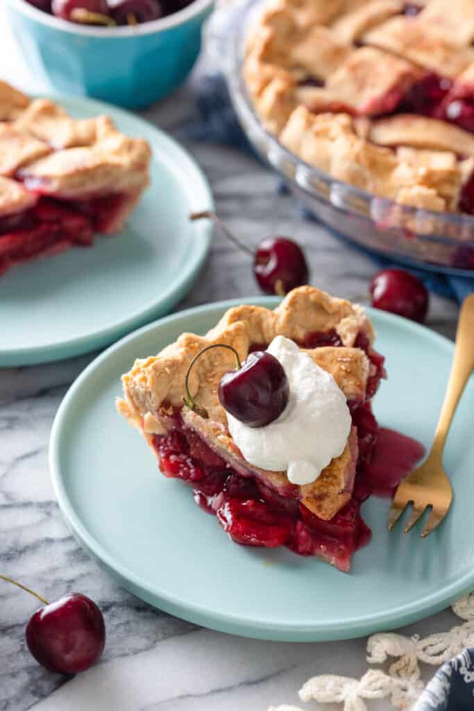 a slice of gluten free cherry pie on a plate with fresh cherries
