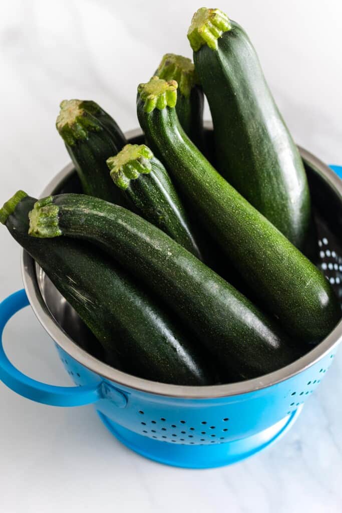 fresh zucchini piled in a colander 