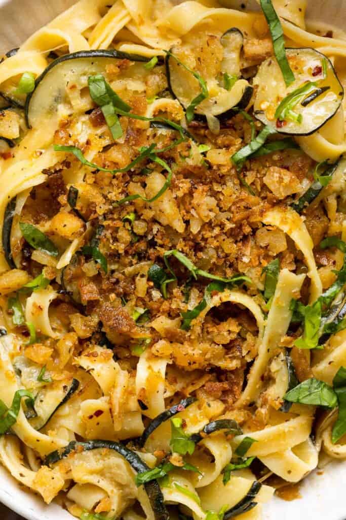 up close tailgate pasta mixed into a lemon zucchini sauce and topped with garlic chili breadbrumbs 