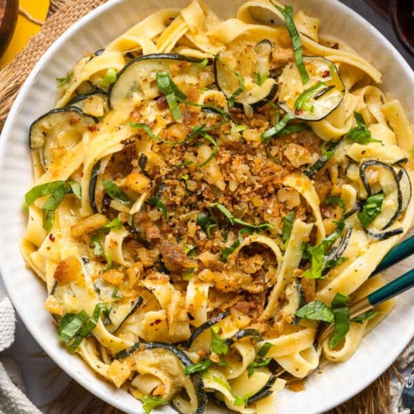 Lemon Zucchini Pasta in a serving dish with serving tongs topped with homemade crispy gluten free garlic chili breadcrumbs