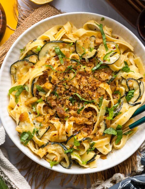 Lemon Zucchini Pasta in a serving dish with serving tongs topped with homemade crispy gluten free garlic chili breadcrumbs