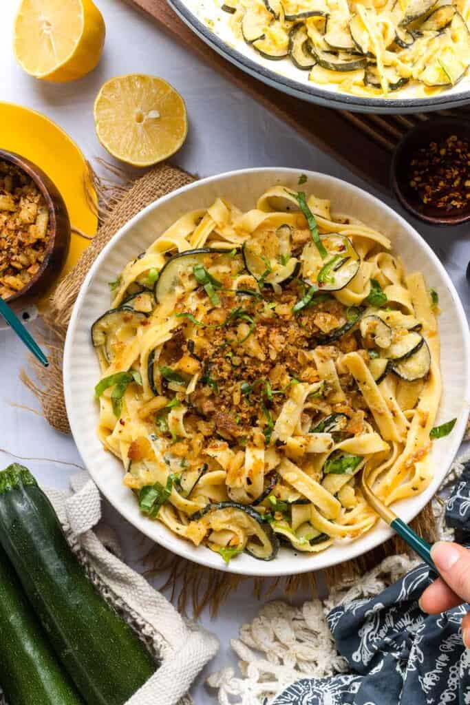 Lemon Zucchini Pasta with garlic chili breadcrumbs getting mixed in a serving dish