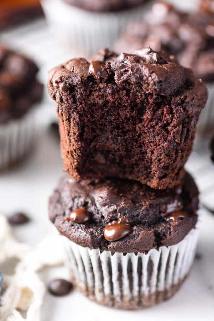 a stack of two Cassava Flour Chocolate Muffins - the top muffin with a bite take out