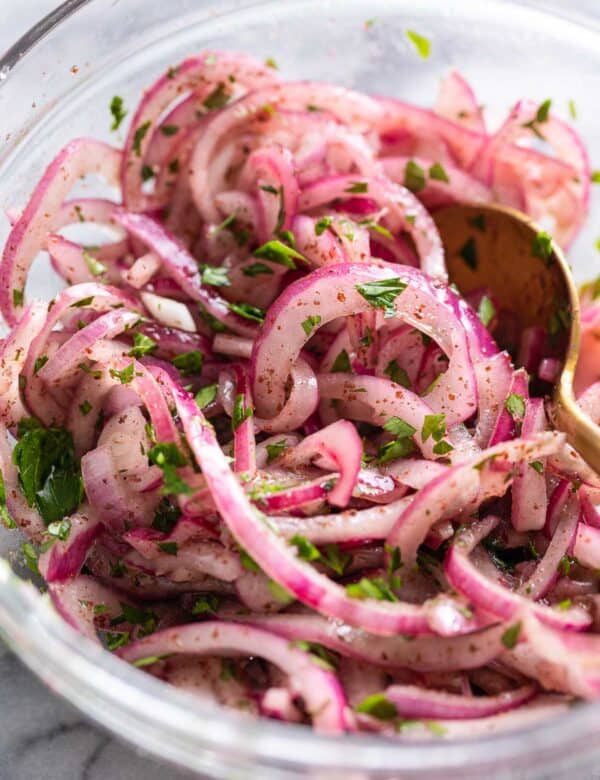 a bowl of thinly Sumac Onions - thinly sliced red onions mixed with sumac and parsley