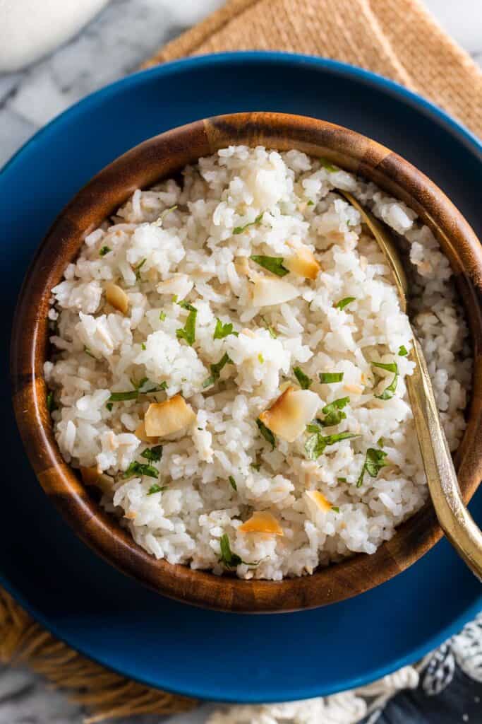 a bowl of Toasted Coconut Rice on plate with a serving spoon tucked into the rice