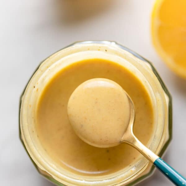 Creamy Lemon Dressing in a jar with a small spoon holding up some dressing