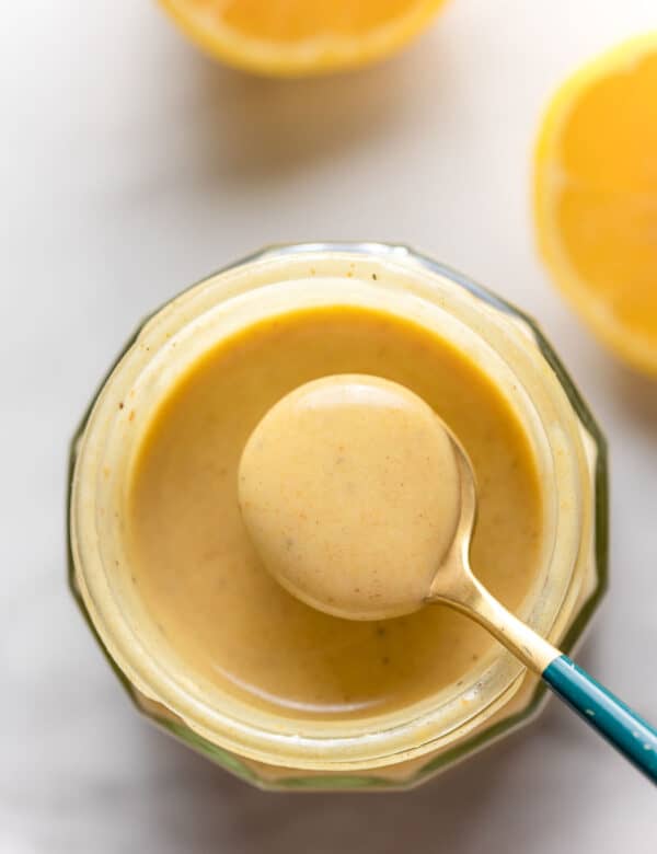 Creamy Lemon Dressing in a jar with a small spoon holding up some dressing