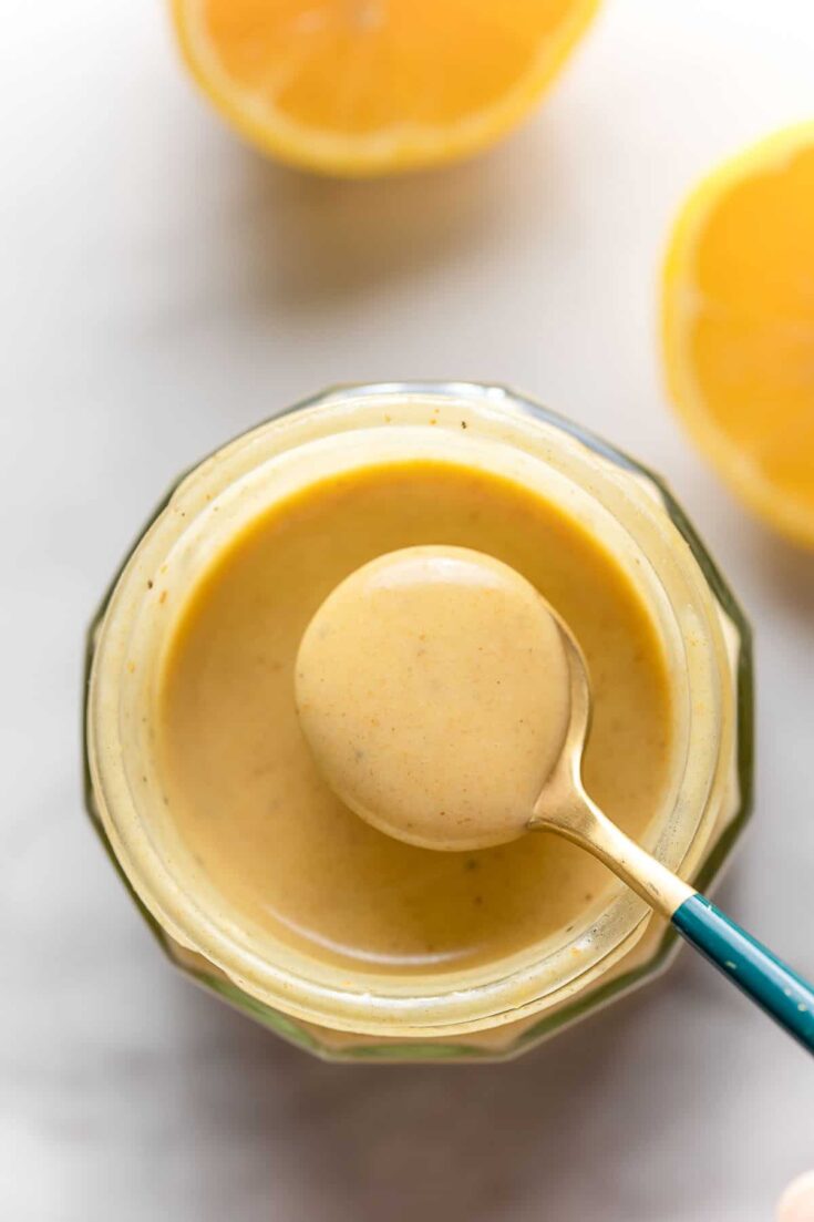 Creamy Lemon Dressing in a jar with a small spoon holding up some dressing