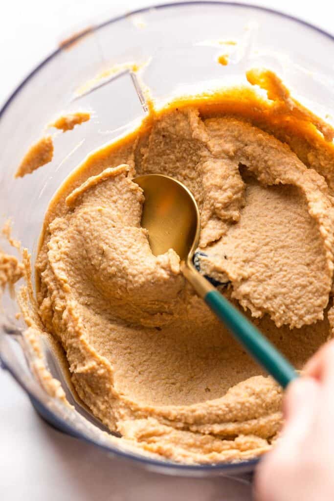 a spoon stirring apple hummus in a food processor just after blending