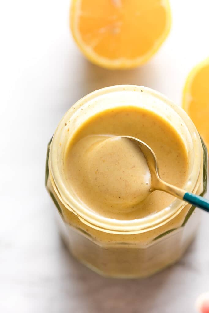 a spoon stirring a jar of lemon dressing