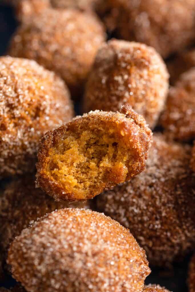 gluten free pumpkin fritters in a cinnamon sugar coating and a bite taken out of one