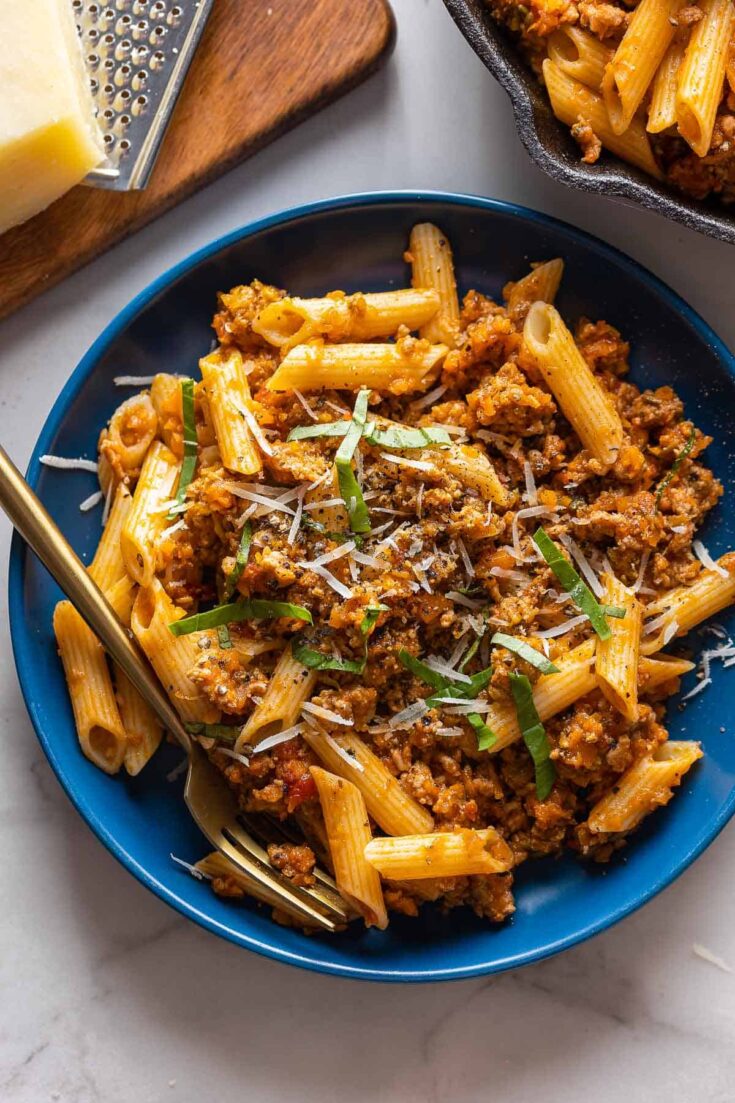 pork ragu on a plate with fresh basil and parmesan