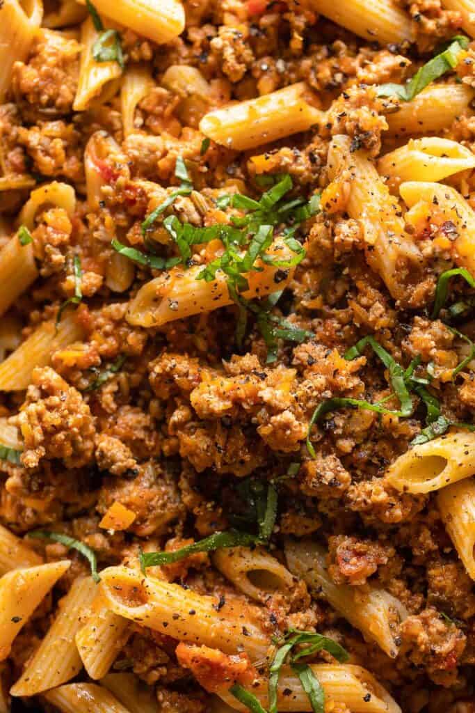 up close image of Pork Ragu with Penne topped with black pepper and fresh basil