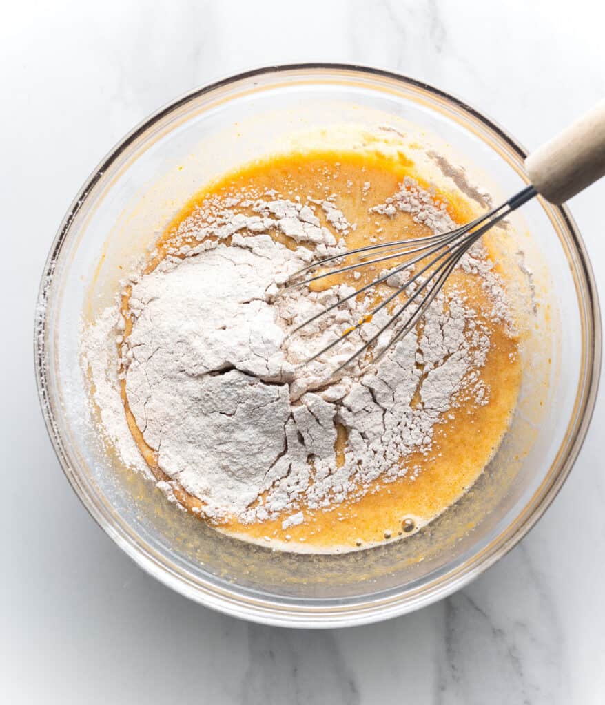 wet and dry ingredients mixing together to make pumpkin roll cake batter