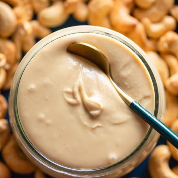 homemade cashew butter in a jar with roasted cashews on the side