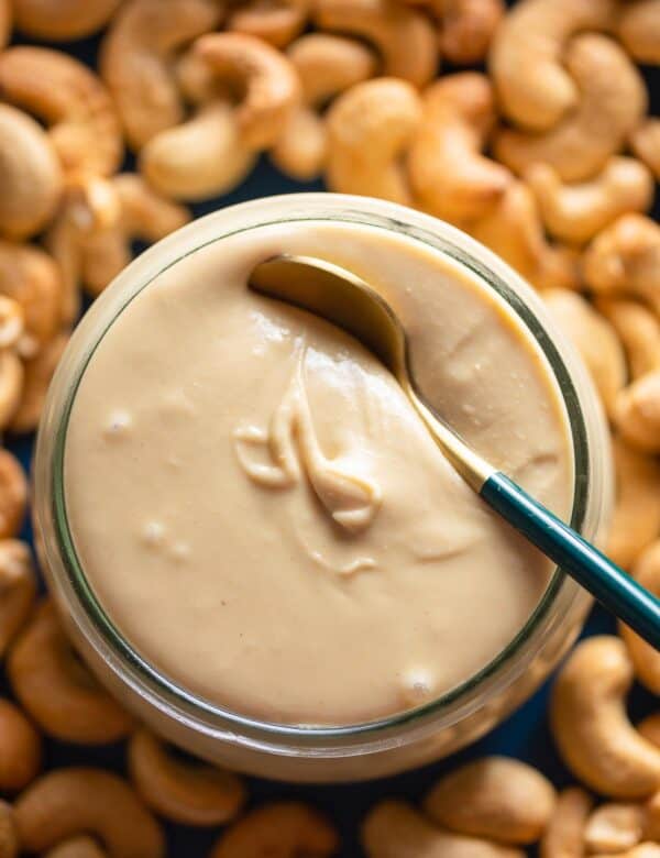 homemade cashew butter in a jar with roasted cashews on the side