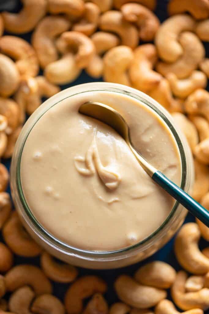 homemade cashew butter in a jar with roasted cashews on the side