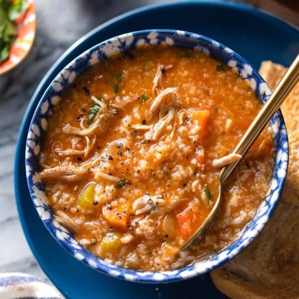 a bowl of Italian Tomato Chicken & Rice Soup on a serving plate with toasted bread