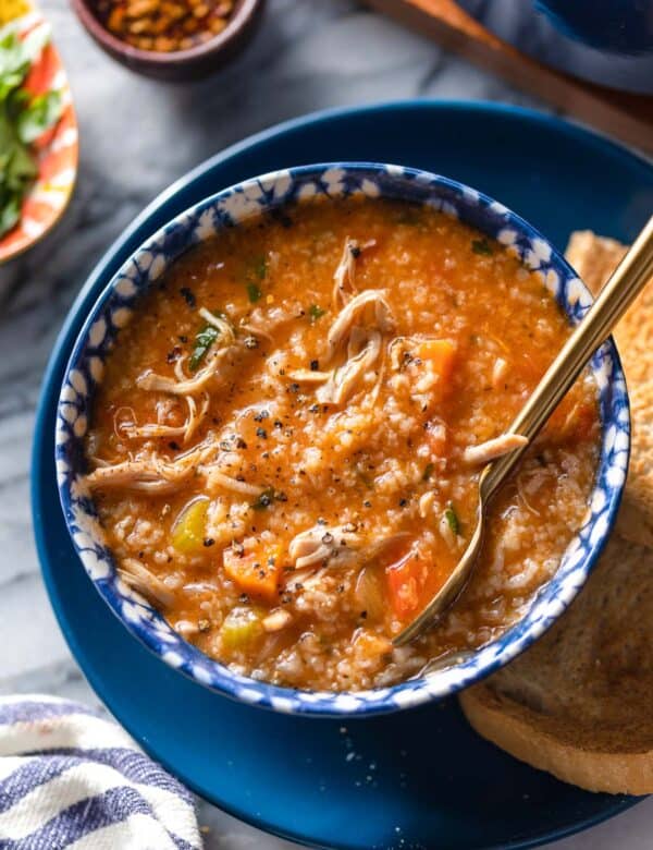 a bowl of Italian Tomato Chicken & Rice Soup on a serving plate with toasted bread