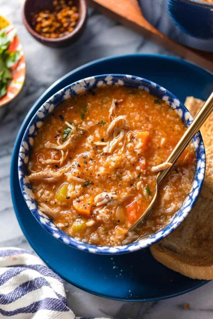 a bowl of Italian Tomato Chicken & Rice Soup on a serving plate with toasted bread