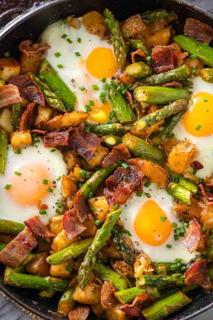 a breakfast skillet made with bacon, potatoes, asparagus and eggs