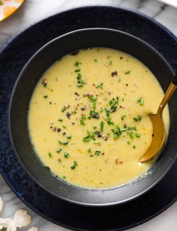 Asparagus Potato Soup in a bowl with a spoon topped with fresh chives