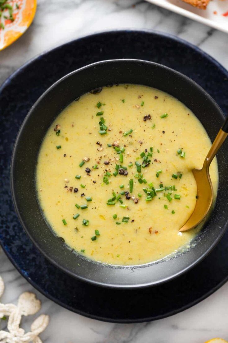 Asparagus Potato Soup in a bowl with a spoon topped with fresh chives