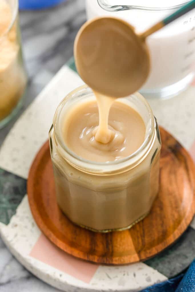 a spoon dripping Homemade Coconut Milk Condensed Milk into a storage jar