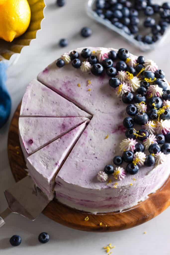a Gluten Free Lemon Cake with Blueberry Filling covered in a blueberry mascarpone frosting and topped with fresh blueberries, lemon zest and little frostings stars piped with a 1C piping tip