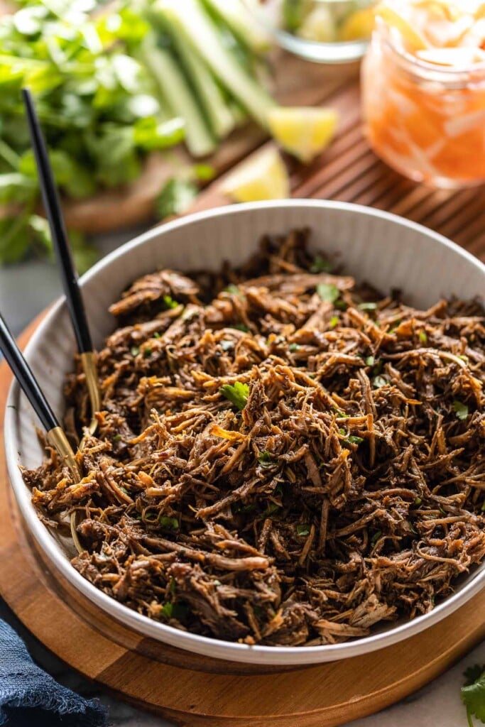 Vietnamese Five Spice Pulled Pork in a serving bowl with serving forks