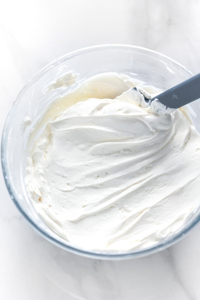 whipped mascarpone frosting in a bowl with a spatula