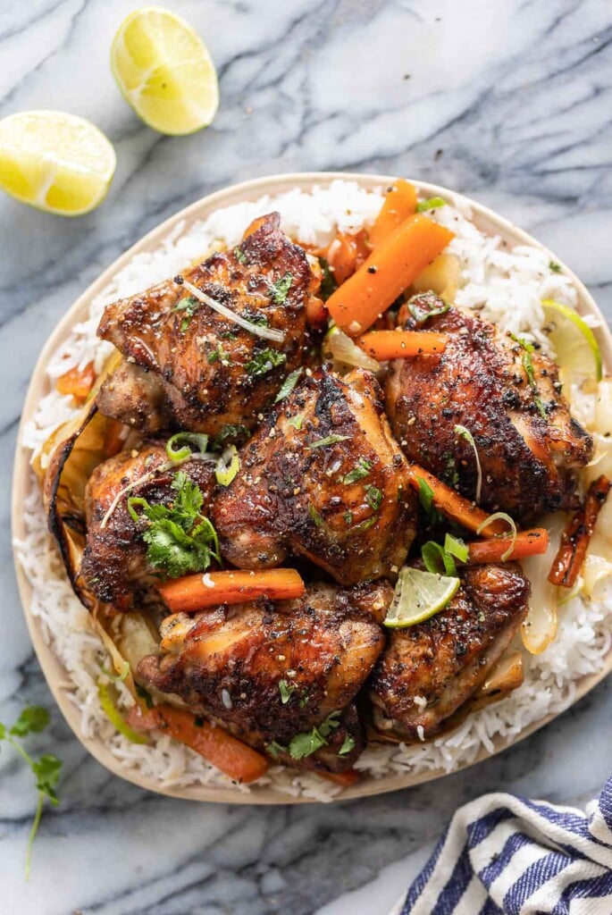five spice chicken thighs over roasted carrot slices and cabbage wedges over a plate of white rice