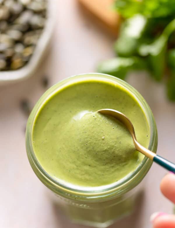 a spoon stirring Cilantro Pepita Dressing in a jar