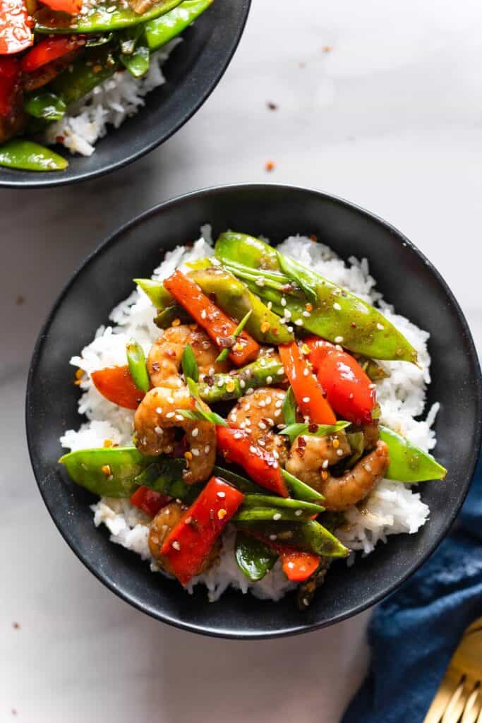Five Spice Shrimp & Vegetable Stir Fry in a bowl with white rice and topped with sesame seeds and chili flakes