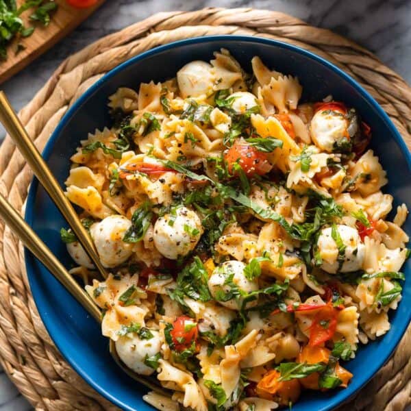 Cherry Tomato Pasta with herby marinated mozzarella balls in a serving bowl with fresh basil