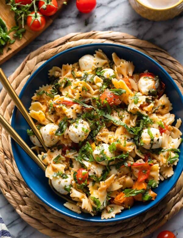 Cherry Tomato Pasta with herby marinated mozzarella balls in a serving bowl with fresh basil