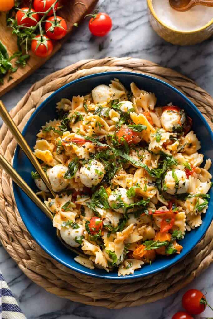 Cherry Tomato Pasta with herby marinated mozzarella balls in a serving bowl with fresh basil