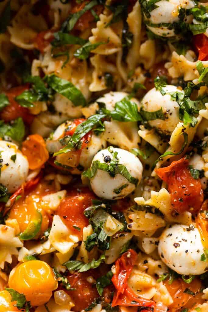 bowtie pasta mixed with burst Cherry Tomatoes, sliced basil and mozzarella pearls 